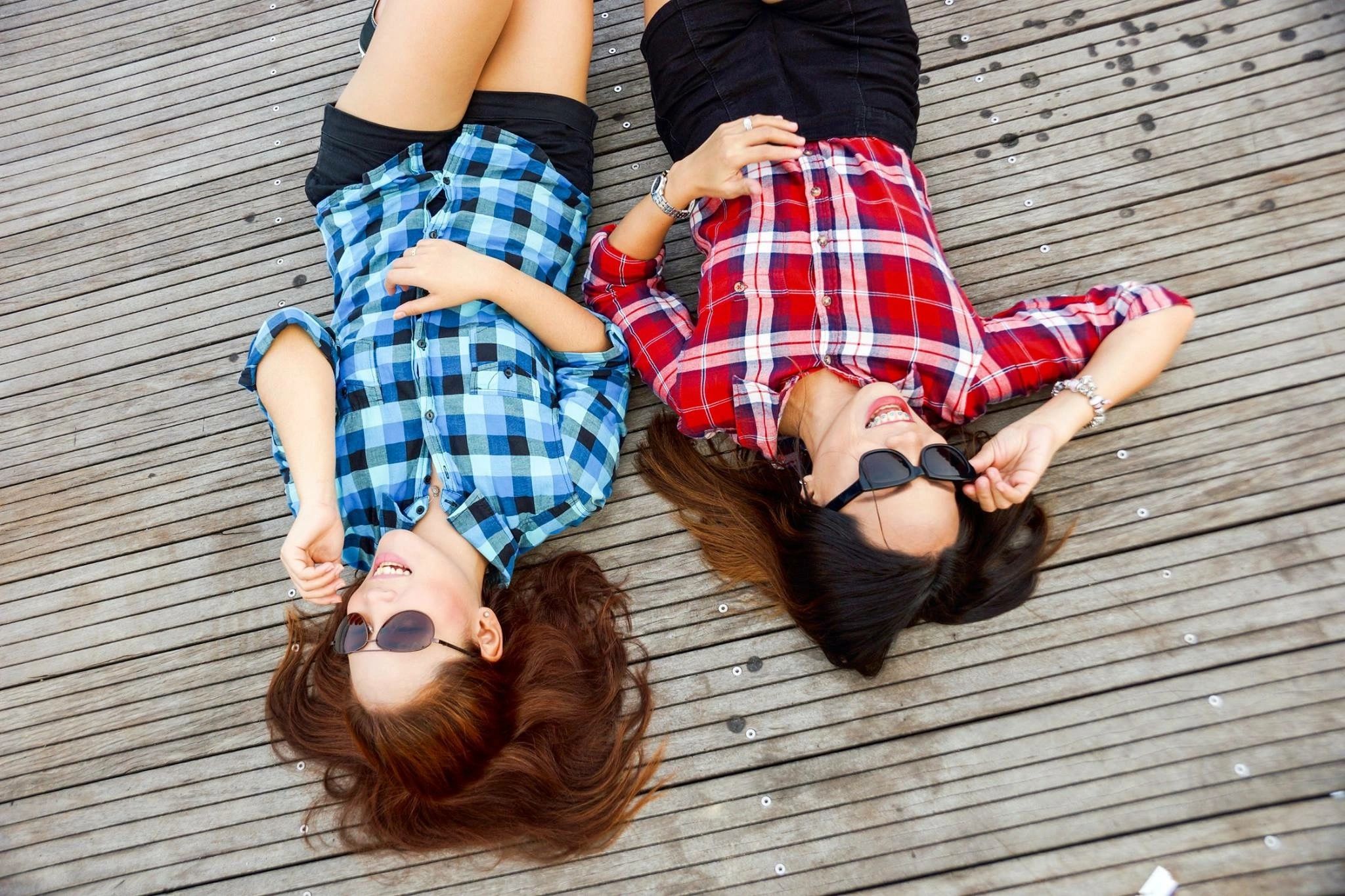 two women lying on the ground relaxing with sunglasses on