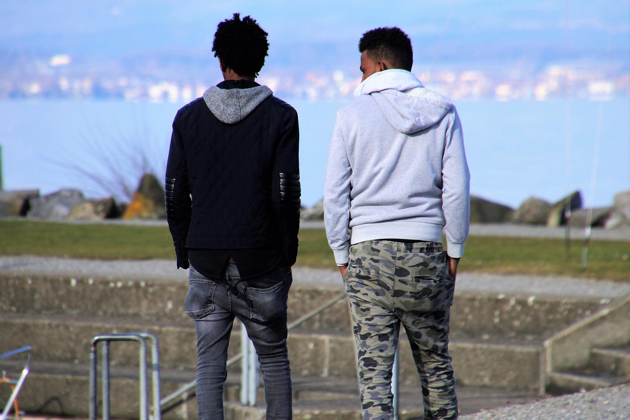 two male friends walking and talking from behind