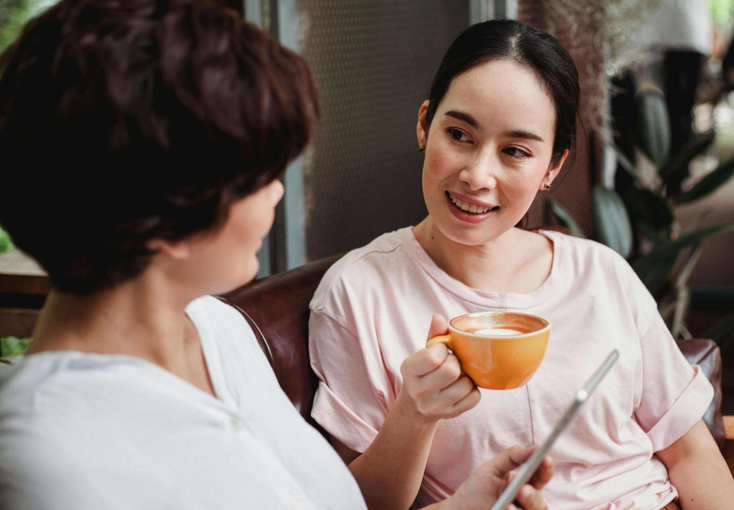 two women friends having coffee with one smiling at her friend